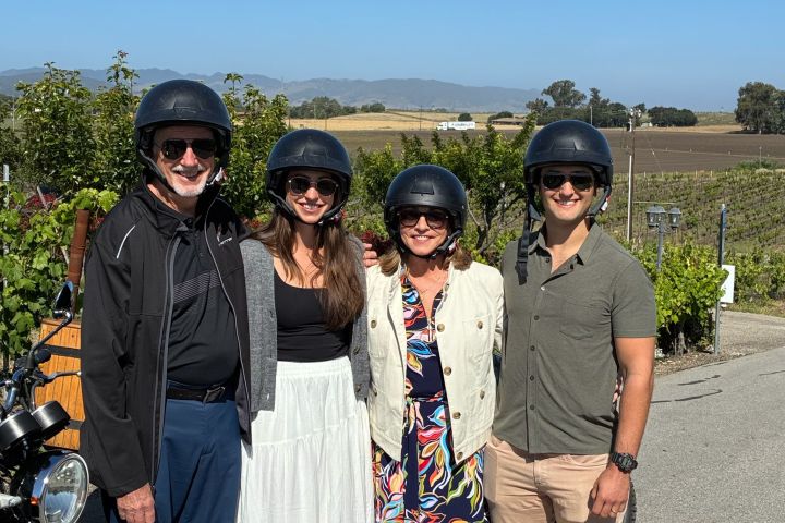 Four people in helmets standing next to motorcycles on a sunny day.